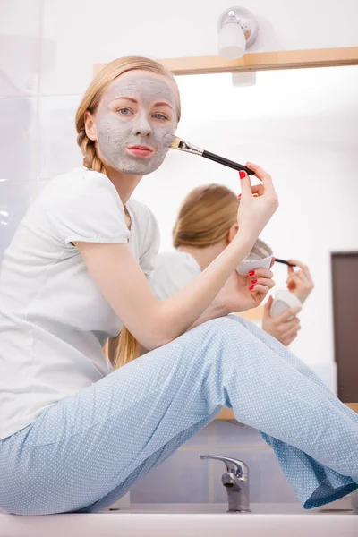 Mujer aplicando con la máscara de barro cepillo de barro en su cara — Foto de Stock