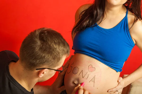 Ventre de femme enceinte, père dessinant dessus — Photo