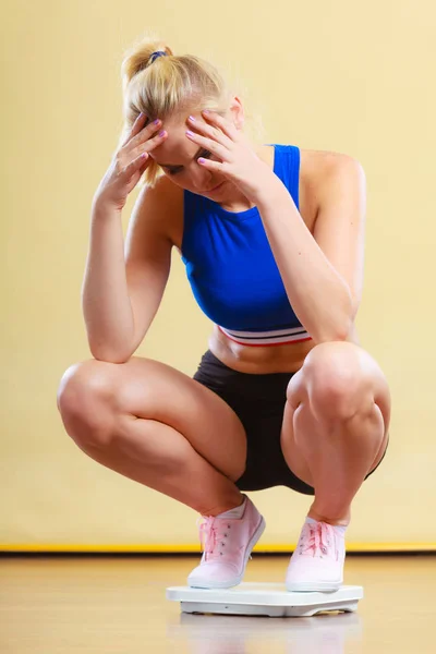 Sportliche Frau auf Gewichtswaage verärgert. — Stockfoto