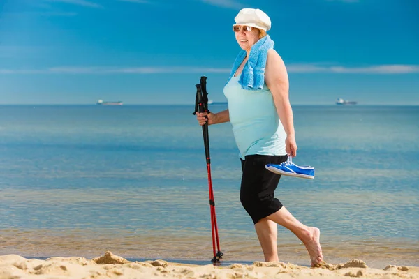 Mulher sênior praticando caminhada nórdica na praia — Fotografia de Stock