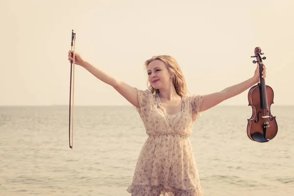 Vrouw op strand in de buurt van de zee houden viool — Stockfoto