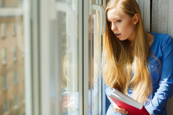 Vrouw leest op vensterbank — Stockfoto