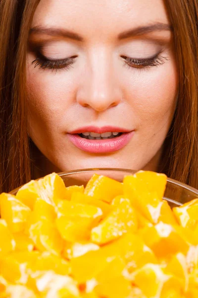 Mujer sostiene cuenco lleno de frutas de naranja en rodajas — Foto de Stock