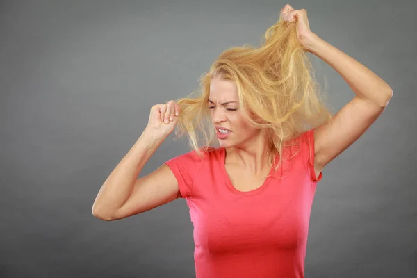 Frustrata donna tenendo i suoi capelli biondi danneggiati — Foto Stock