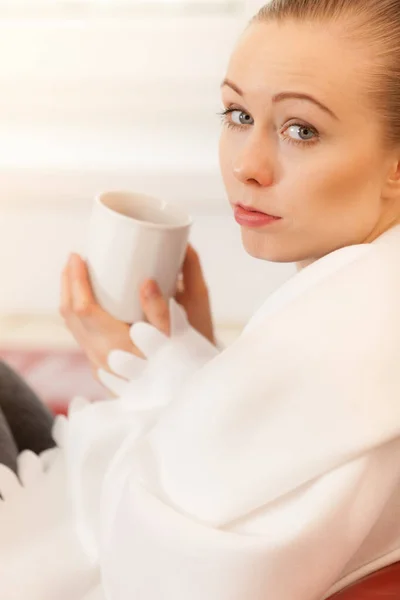 Kobieta, leżąc na kanapie pod koc picia herbaty — Zdjęcie stockowe