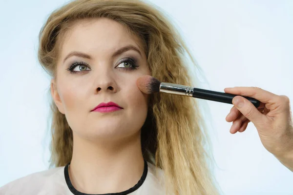 Maquiagem artista aplicando com escova rouge no cheque feminino — Fotografia de Stock