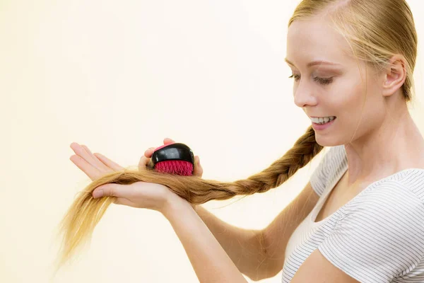 Blonde girl with long braid hair holds brush — Stock Photo, Image