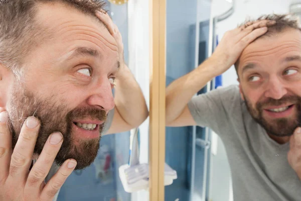 Ευτυχισμένος άνθρωπος ενηλίκων κοιτάζει μαλλιά στον καθρέφτη — Φωτογραφία Αρχείου