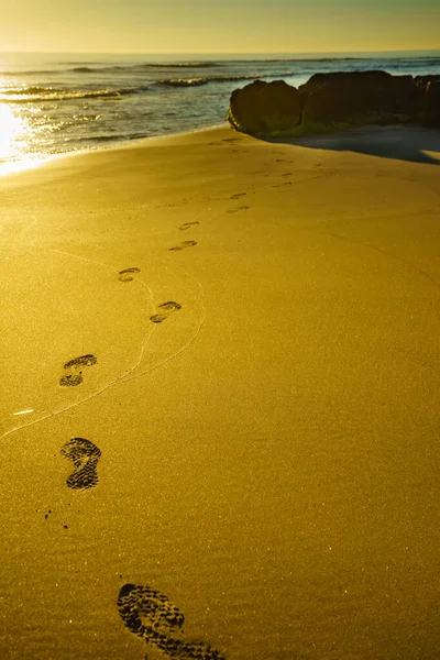 Sunset and footprints on beach — Stock Photo, Image