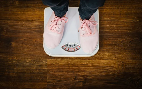 Mulher com sapatilhas rosa na balança de peso do banheiro — Fotografia de Stock