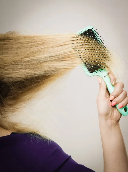 Mulher loira irreconhecível escovando cabelo — Fotografia de Stock