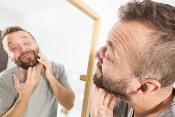 Uomo guardando la barba nello specchio — Foto Stock