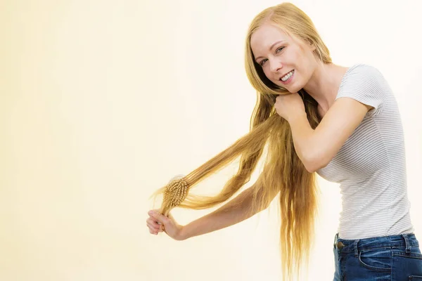 Chica rubia cepillándose el pelo largo — Foto de Stock