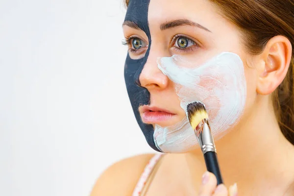 Kız siyah maske üzerinde yarım yüz uygulamak beyaz çamur — Stok fotoğraf
