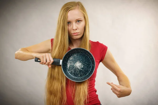 Angry girl holding scratched frying pan — Stock Photo, Image