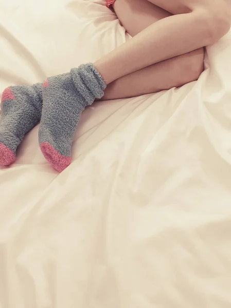 Kobieta leżąca na łóżku w futrzanych skarpetkach — Zdjęcie stockowe