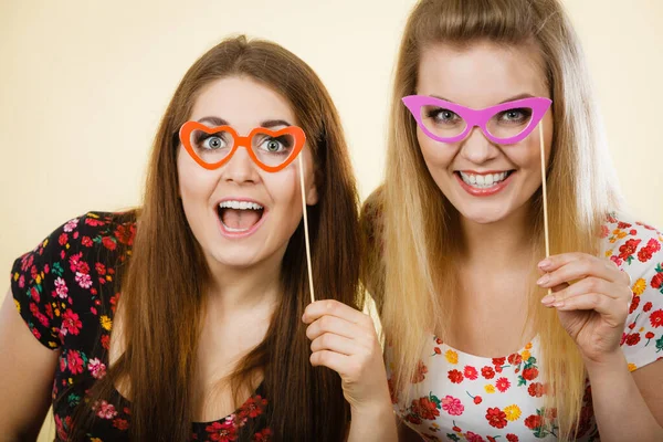 Two happy women holding fake eyeglasses on stick — Stock Photo, Image