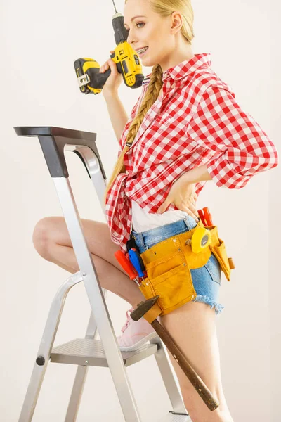 Woman on ladder using drill