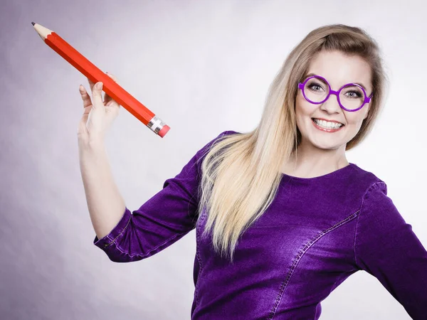 Mujer sonriente sostiene un lápiz grande en la mano — Foto de Stock