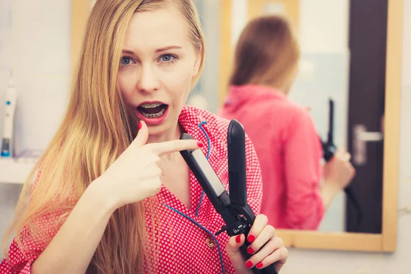 Vrouw straighten van haar lang blond haar — Stockfoto