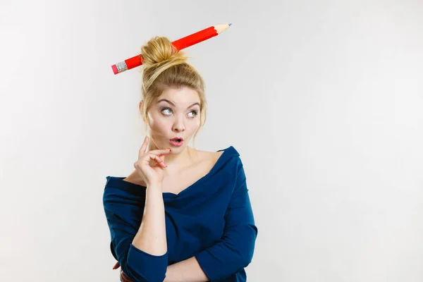 Pensando mujer rubia teniendo lápiz grande en el pelo — Foto de Stock