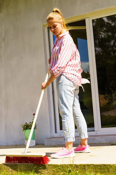 Donna che usa scopa per pulire patio cortile — Foto Stock