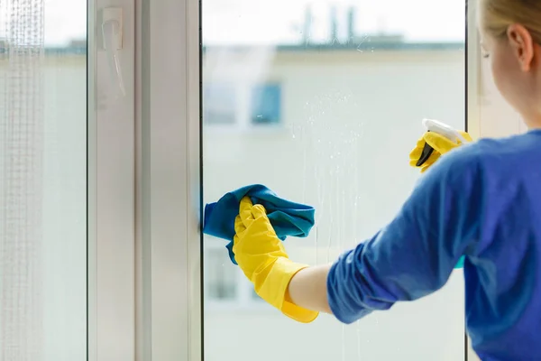 Meisje schoonmaken venster thuis met behulp van wasmiddel doek — Stockfoto