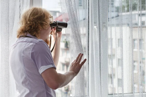 Man met verrekijker die buren bespioneert — Stockfoto