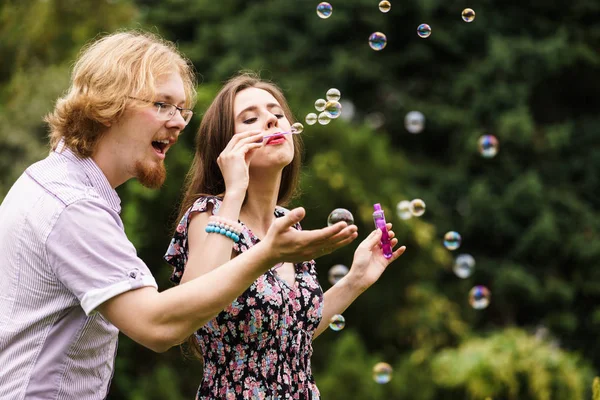 Pareja soplando burbujas de jabón, divirtiéndose — Foto de Stock