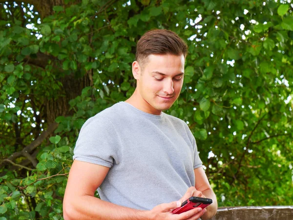 Muž pomocí mobilního telefonu v parku — Stock fotografie