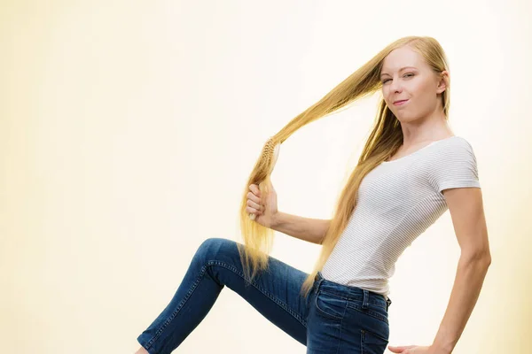 Menina loira escovando seu cabelo longo — Fotografia de Stock