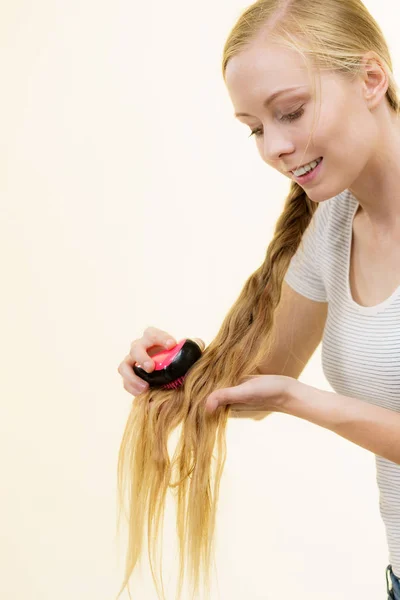 Blonde girl with long braid hair holds brush — ストック写真