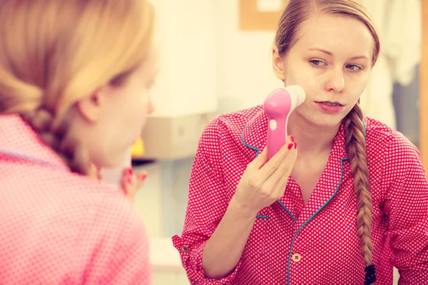 Mujer usando cepillo de limpieza facial en la cara — Foto de Stock