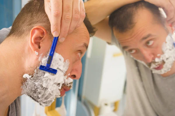 Guy scheren van zijn baard in badkamer — Stockfoto