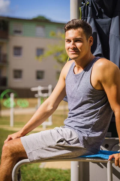 Hombre que utiliza la máquina de entrenamiento de deporte al aire libre — Foto de Stock