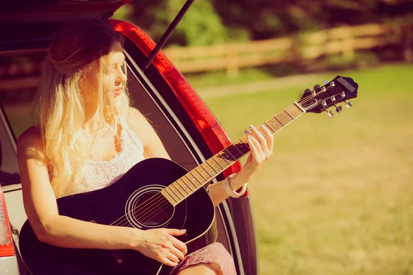 Hippie vrouw gitaarspelen in van auto — Stockfoto