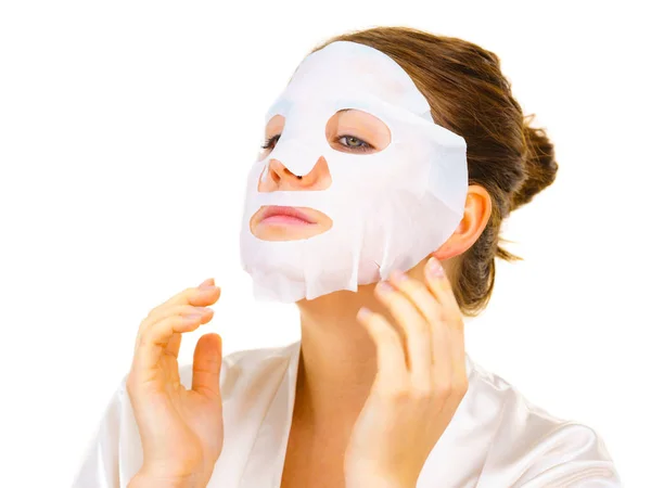 Mujer aplicando máscara de hoja en la cara —  Fotos de Stock