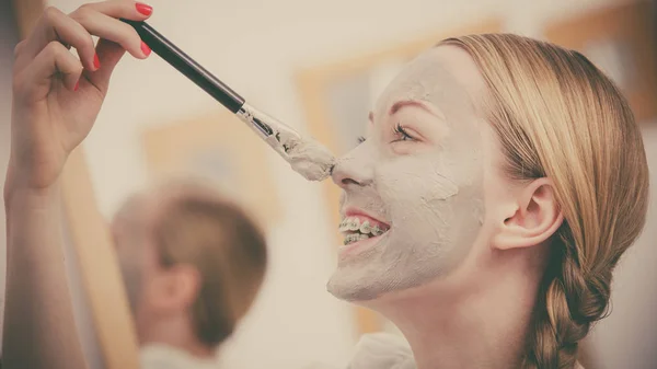 Donna che si applica con maschera di fango di argilla pennello al viso — Foto Stock