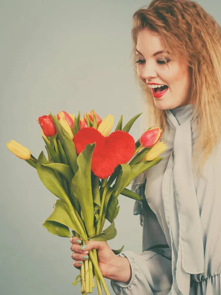 Mulher segura tulipas e coração vermelho — Fotografia de Stock