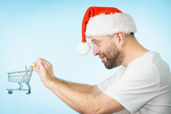 Mann mit Weihnachtsmütze hält leeren Warenkorb — Stockfoto