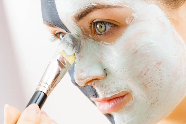 Mädchen schwarze Maske auf halbem Gesicht weißen Schlamm auftragen — Stockfoto