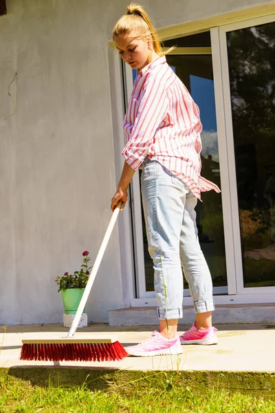 Mujer usando escoba para limpiar patio trasero —  Fotos de Stock