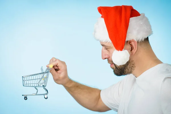 Mann mit Weihnachtsmütze hält leeren Warenkorb — Stockfoto