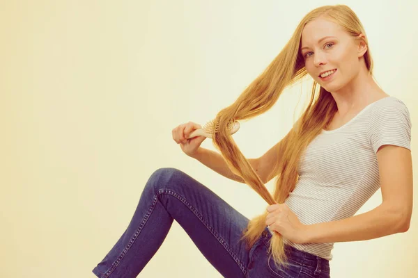 Blond meisje borstelen haar lange haar — Stockfoto