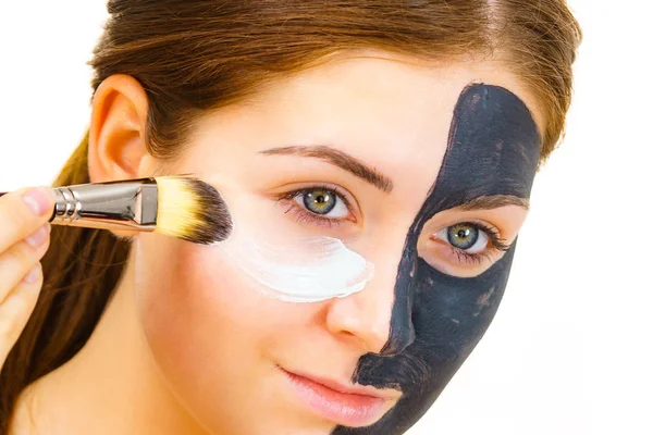 Meisje zwart masker op halve gezicht apply witte modder — Stockfoto
