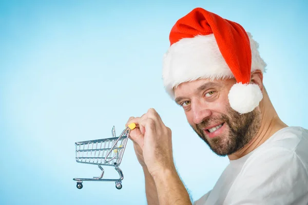 Mann mit Weihnachtsmütze hält leeren Warenkorb — Stockfoto