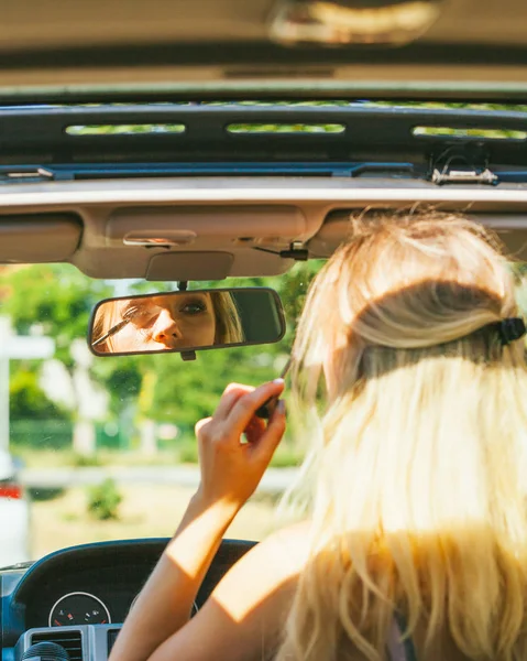 女の子は車を運転しながらメイクアップを適用します. — ストック写真