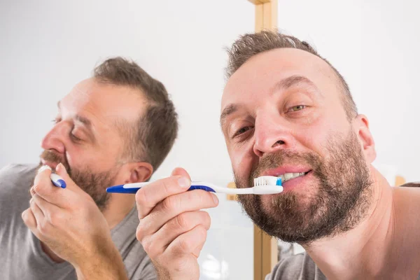 Uomo lavarsi i denti in bagno — Foto Stock