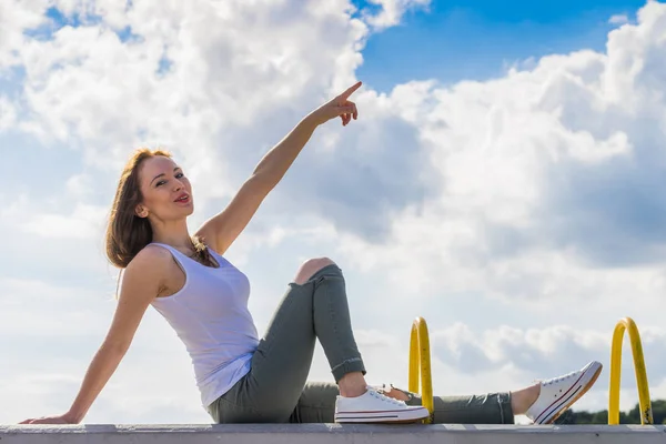 Chica con pantalones y zapatillas de deporte apuntando al aire libre —  Fotos de Stock