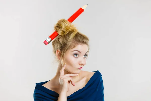 Pensando mujer rubia teniendo lápiz grande en el pelo — Foto de Stock